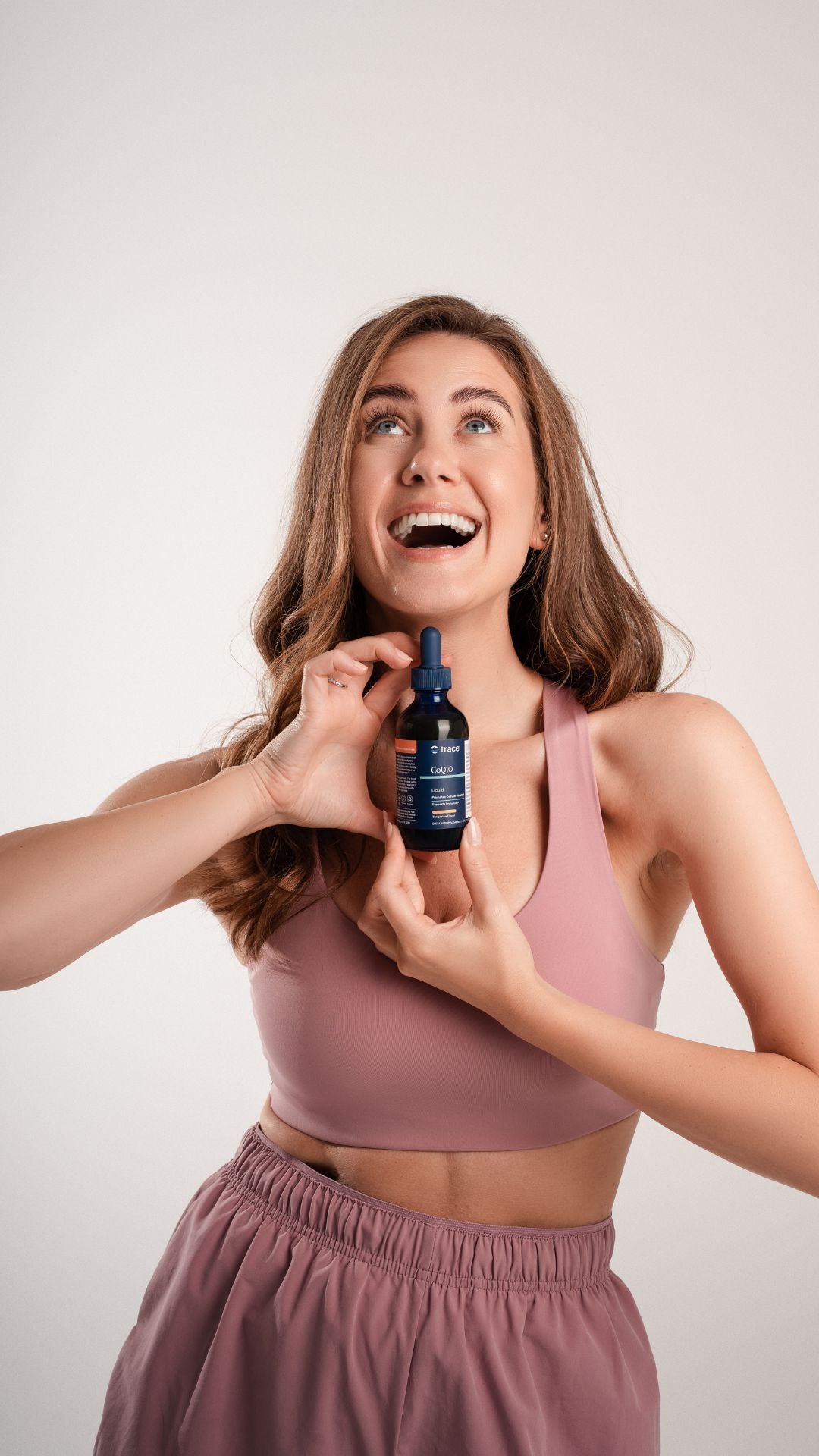 Moteris laiko kofermento Q10 maisto papildą rankose ir šypsosi.