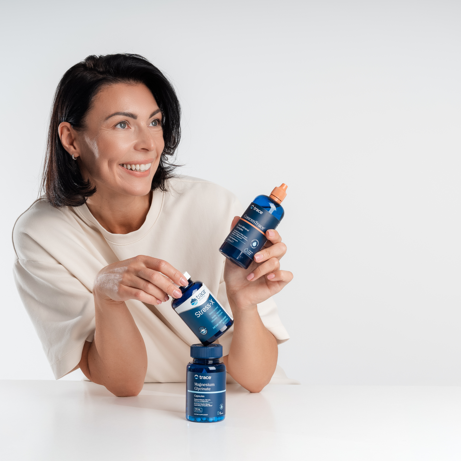 Moteris šypsosi ir laiko Trace Minerals maisto papildus: magnio glicinatą, B grupės vitaminą Stress-X ir Concentrace joninius jūros mineralus.